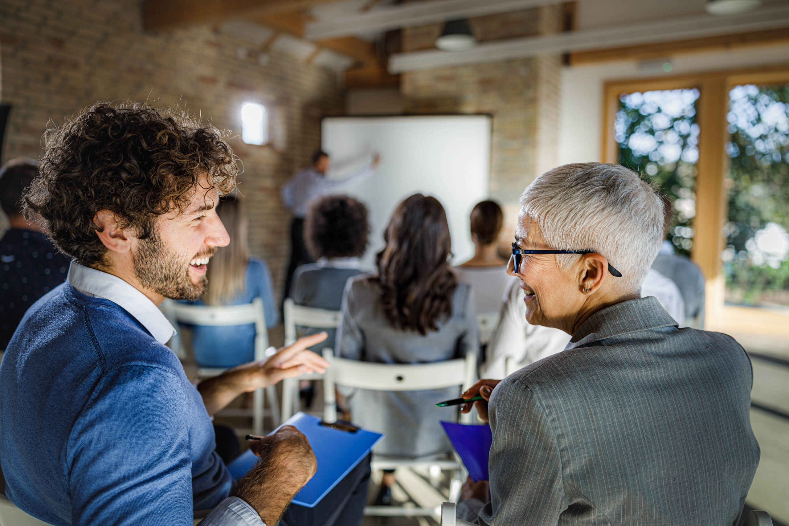 Happy entrepreneurs communicating during an education event in board room.